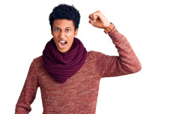 Genç Afro-Amerikan adam, günlük kazak ve eşarp giyer kızgın ve kızgın yumruk kaldırırken öfkeyle bağırır. öfke ve agresif konsept. 