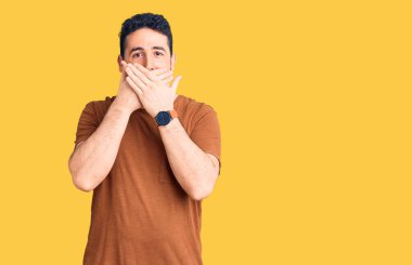 Gündelik kıyafetler giyen genç İspanyol adam yanlışlıkla elleri ile ağzını kapatırken şok oldu. gizli kavram. 