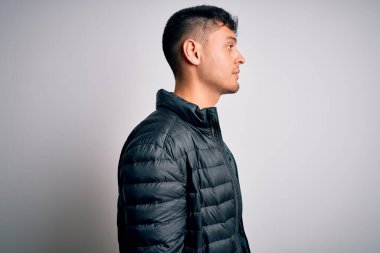 Genç, yakışıklı, kışlık ceketli, beyaz, soyutlanmış arka planda duran, kendine güvenen, doğal yüzüyle poz veren yakışıklı bir İspanyol..