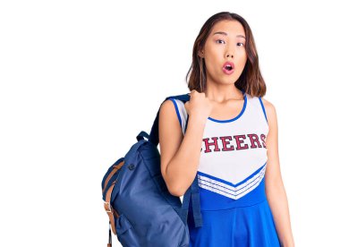 Genç, güzel Çinli kız amigo üniforması giyiyor. Öğrenci çantası taşıyor. Ağzını açıp şaşkınlıktan ağzı açık kalıyor. 