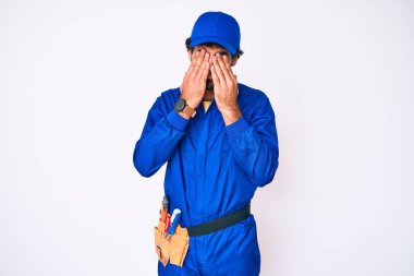 Kıvırcık saçlı yakışıklı genç adam ve ayı terbiyecisi üniforması. Yorgunluk ve baş ağrısı için gözlerini ovuşturuyor. Uykulu ve yorgun yüz ifadesi. görme sorunu 