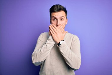Mor izole arka plan üzerine günlük süveter giyen yakışıklı beyaz bir adam ağzını yanlışlıkla ellerle kapatarak şok etti. Gizli konsept.