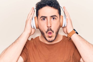 Genç İspanyol adam müzik dinliyor kulaklık takıyor. Korkmuş ve şaşırmış bir şekilde ağzı açık, inançsız bir yüz. 