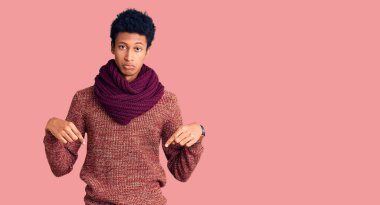 Genç Afro-Amerikan adam, günlük kışlık süveter ve fular giymiş üzgün ve üzgün görünüyor, parmaklarıyla yönü gösteriyor, mutsuz ve depresif.. 