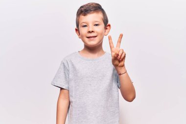 Gayri resmi giyinen, gülen, kameraya göz kırpan, zafer işareti yapan sevimli sarışın çocuk. İki numara.. 