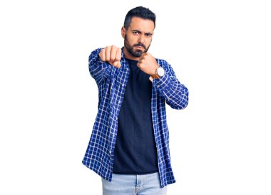 Latin kökenli genç adam gündelik kıyafetler giyiyor. Yumruk yumruğa dövüşüyor, agresif ve öfkeli saldırı, tehdit ve şiddet uyguluyor. 