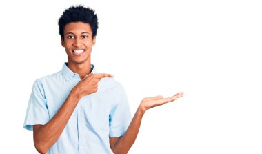 Genç Afro-Amerikalı sıradan kıyafetler giyen adam kameraya hayret ediyor ve gülümsüyor.. 
