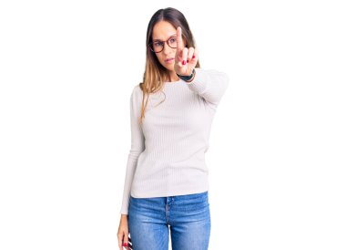 Güzel esmer, beyaz süveter giyen, gözlüklü, parmağını kaldırmış ve kızgın bir ifade takınan genç bir kadın. 