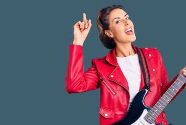 Elektro gitar çalan genç ve güzel bir kadın bir fikre ya da soru işaretine şaşırdı ve mutlu bir yüzle işaret etti. 