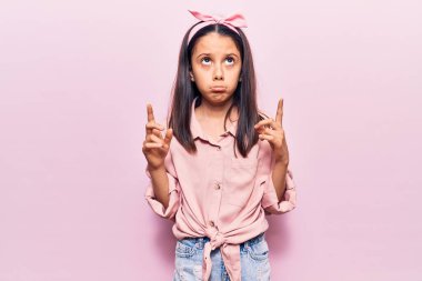 Güzel bir kız çocuğu gündelik giysiler içinde üzgün ve üzgün görünüyor, parmaklarıyla yön gösteriyor, mutsuz ve depresif.. 