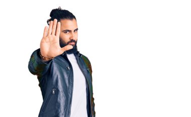 Deri ceket giyen genç bir Arap avucuyla şarkı söylemeyi kesiyor. Yüzünde olumsuz ve ciddi bir jest olan uyarı ifadesi. 