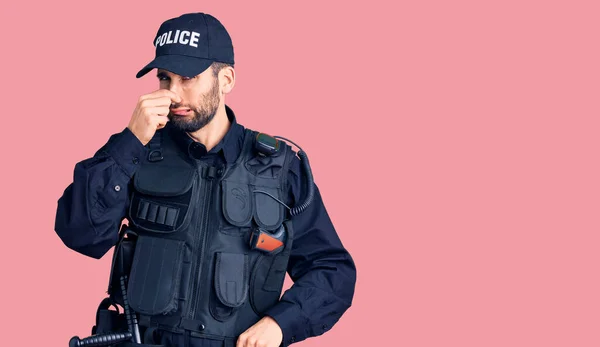 Joven Hombre Guapo Con Barba Vistiendo Uniforme Policía Oliendo Algo —  Fotos de Stock