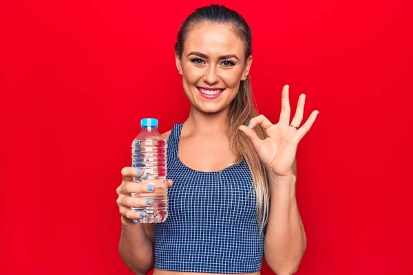 Ung Vacker Blond Kvinna Dricka Flaska Vatten Över Isolerad Röd — Stockfoto