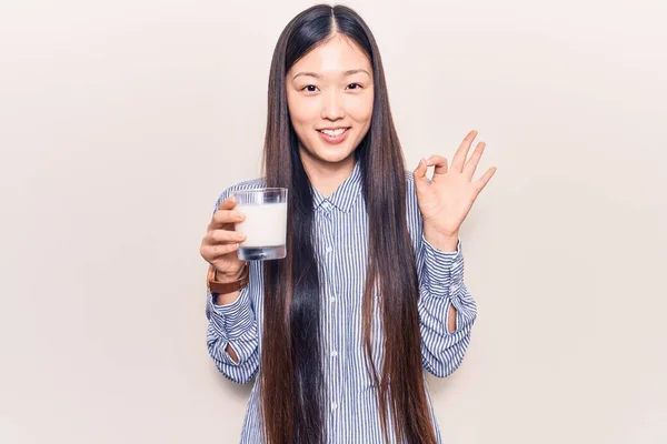 Młoda Piękna Chinka Pije Szklankę Mleka Robi Znak Palcami Uśmiechając — Zdjęcie stockowe