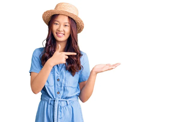 年轻美丽的中国姑娘戴着夏帽 手牵着手 指指点点着相机 脸上挂着惊讶的笑容 — 图库照片