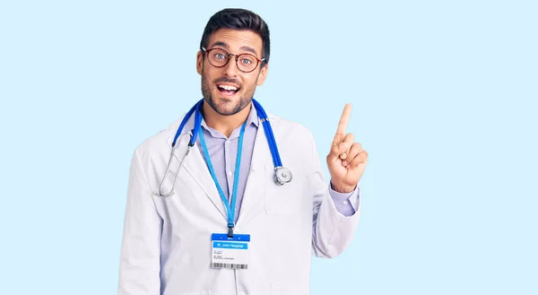 Joven Hombre Hispano Con Uniforme Médico Estetoscopio Apuntando Con Dedo —  Fotos de Stock