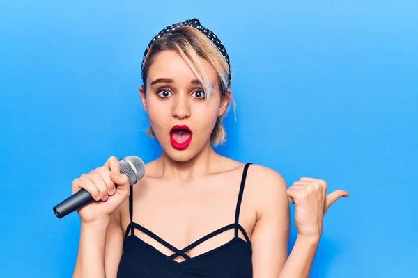 Jovem Bela Mulher Loira Cantando Música Usando Microfone Apontando Polegar — Fotografia de Stock