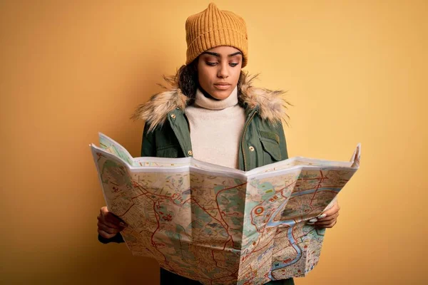 African american skier tourist girl wearing snow sportswear and ski goggles holding city map with a confident expression on smart face thinking serious