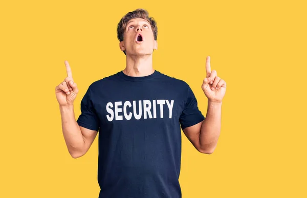Mladý Pohledný Muž Bezpečnostní Tričko Užaslý Překvapený Vzhlíží Ukazuje Prsty — Stock fotografie