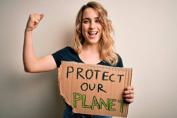 Young activist woman asking for environment holding banner with protect planet message screaming proud and celebrating victory and success very excited, cheering emotion