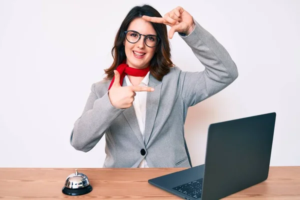 리셉션에서 일하는 아름다운 여자는 노트북으로 웃으면서 얼굴로 손가락으로 프레임을 만들었다 — 스톡 사진