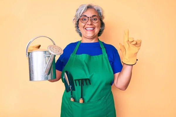 Ältere Hispanische Grauhaarige Frau Gärtnerschürze Und Handschuhen Mit Gießkanne Überrascht — Stockfoto