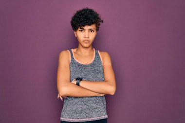 Genç ve güzel afro-amerikan Afro-kadın spor yapıyor spor kıyafetleri giyiyor kuşkucu ve gergin, yüzünde çapraz kollarla onaylamayan bir ifade. Negatif kişi.