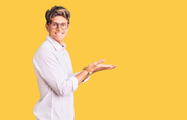 İş kıyafetleri ve gözlük takan genç yakışıklı adam avuçlarını açıp fotokopi alanını gösteriyor. Reklam sunuyor, gülümsüyor, mutlu bir şekilde gülümsüyor. 