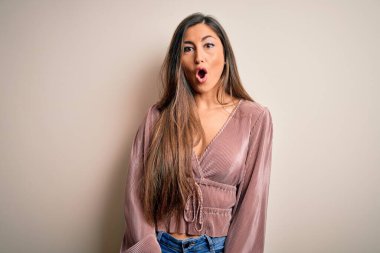 Genç, güzel, zarif, uzun saçlı, izole edilmiş arka planda duran zarif bir kadın. Şaşırmış ve korkmuş bir ifade, korku ve heyecanlı bir yüz ifadesi var..