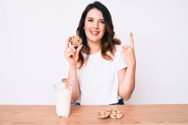 Genç, güzel, esmer bir kadın bir bardak taze süt ve kurabiyeler içiyor. Bir fikir ya da soru işareti ile şaşırmış, mutlu bir yüzle, bir numara. 