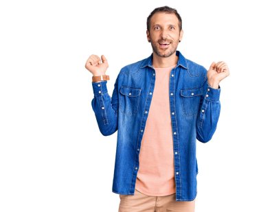 Gündelik giysiler giyen genç yakışıklı adam şaşkınlık ve şaşkınlık içinde kollarını kaldırarak ve gözlerini açarak başarıyı kutluyor. Kazanan konsept. 