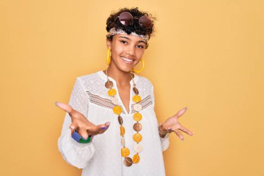 Genç, Afro-Amerikan Afro-Amerikan, güneş gözlüğü takan, aksesuar takan neşeli gülümseyen, dost canlısı, olumlu ve kendinden emin bir selamlama.