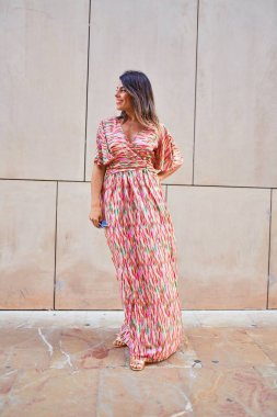 Güzel, genç bir kadın, şık kıyafetler giyip sokakta yürüyor.