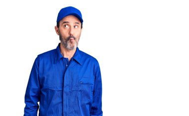 Tamirci üniforması giyen orta yaşlı yakışıklı adam dudaklarıyla balık suratı yapıyor, çılgınca ve komik bir jest. Komik ifade. 