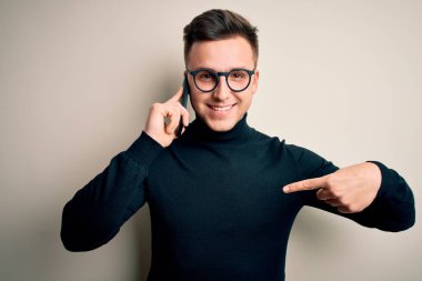 Genç, yakışıklı, beyaz bir adam akıllı telefondan konuşuyor. Şaşırmış bir yüz ifadesiyle kendini işaret ediyor.