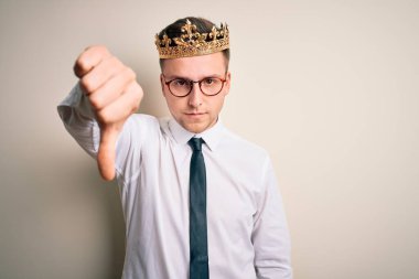 İzole edilmiş arka planda altın taç takan yakışıklı beyaz bir işadamı mutsuz ve kızgın görünüyor. Reddedilmiş ve olumsuz bir hareket yapıyor. Kötü ifade.