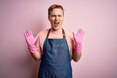 Önlük ve eldivenlerle ev işi yapan genç, yakışıklı, kızıl saçlı temizlikçi. Başarı için çılgın ve çılgın bir kutlama yapıyor. Kolları havada, gözleri kapalı, heyecanlı çığlıklar atıyor. Kazanan konsept