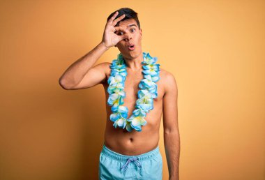 Tatilde olan yakışıklı bir turist mayo giyiyor ve Hawaii çiçekleri yapıyor. Şaşırmış yüz ifadesiyle şaşırmış, parmaklarından bakan gözler. İnançsız ifade.