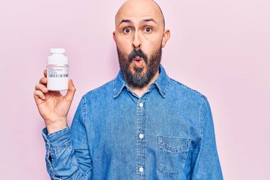 Genç yakışıklı adam hapları tutuyor. Korkmuş ve ağzı açık kalmış, şaşırmış ve şaşırmış. 