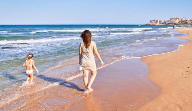 Güzel anne ve kız sahilde oynuyorlar.