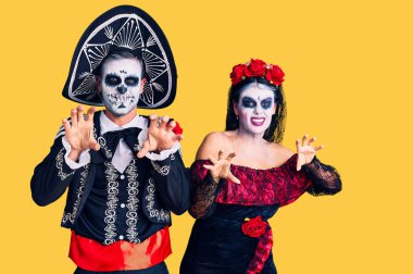 Arka planda Meksika kostümlü genç bir çift gülümsüyor kedi gibi pençe hareketi yapıyor, agresif ve seksi bir ifade. 