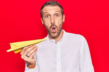 Elinde kağıt uçak tutan genç yakışıklı adam şaşıracak şekilde ağzı açık kalmış, korkmuş ve hayrete düşmüştü. 