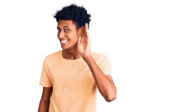 Genç Afro-Amerikan bir adam, günlük giysiler giymiş, ağzı kulaklarına varan bir gülümsemeyle dedikodu ve söylentileri dinliyor. Sağırlık kavramı. 