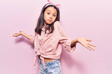 Sıradan kıyafetler giyen, elleri ve kolları havada, kafası karışmış güzel bir kız çocuğu. şüphe kavramı. 