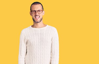 Gündelik kıyafetler giyen ve gözlük takan genç yakışıklı adam kameraya seksi bir ifadeyle bakıyor, neşeli ve mutlu bir yüzle.. 