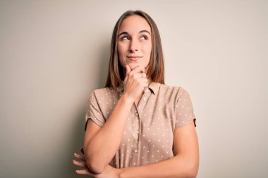 İzole edilmiş beyaz arka plan üzerinde dikilen, soru soran, düşünceli bir kadın. Düşünceli bir yüzle gülümsüyor. Şüphe kavramı.