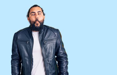 Deri ceket giyen genç bir Arap dudaklarıyla balık suratı yapıyor, çılgınca ve komik bir jest. Komik ifade. 