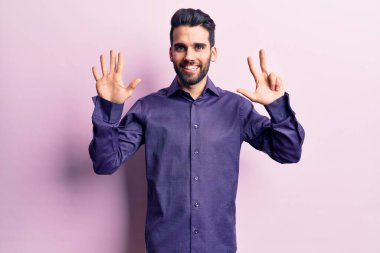 Sakallı, sıradan tişörtlü, genç ve yakışıklı bir adam sekiz numaralı parmaklarıyla onu gösterirken kendinden emin ve mutlu gülümsüyor.. 