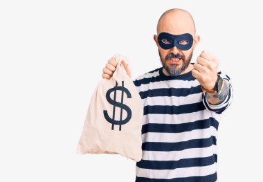 Hırsız maskesi takan genç bir adam. Elinde dolar sembolü olan para çantası var. Öfkeyle bağırıyor, öfkeyle bağırıyor ve el kaldırıyor. 