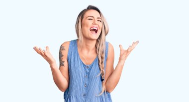 Young beautiful blonde woman wearing casual sleeveless t-shirt celebrating mad and crazy for success with arms raised and closed eyes screaming excited. winner concept  clipart